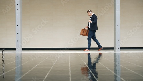 Side view of business people wear his headphone and walking to workplace along the street in urban city. Professional project manager going to meeting while listen relaxing music from headset. Urbane. © Summit Art Creations