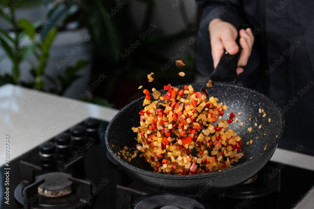 Close up of Chef cook hands cooking and toss roasted onion, pepper, Shiitake mushrooms, cabbage, garlic in frying wok pan on gas stove. Flying food levitation. Close up of Chef cook hands cooking and toss roasted onion, pepper, Shiitake mushrooms, cabbage, garlic in frying wok pan on gas stove. Flying food levitation.