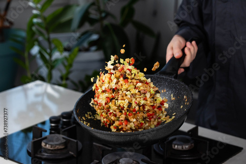 Bilde på lerret Close up of Chef cook hands cooking and toss roasted onion, pepper, Shiitake mushrooms, cabbage, garlic in frying wok pan on gas stove