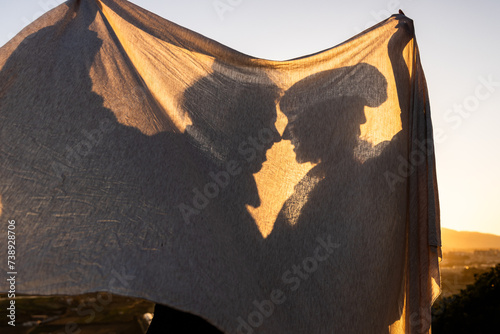 Shadow of couple in scarf against light in nature photo