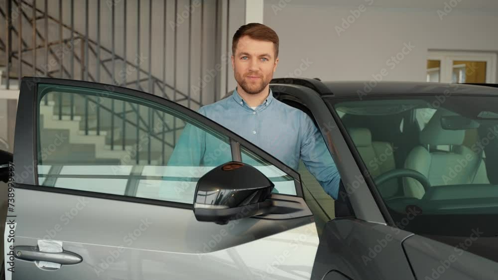 Man near a car in car dealership showroom. Right hand drive car Man near a car in car dealership showroom. Right hand drive car
