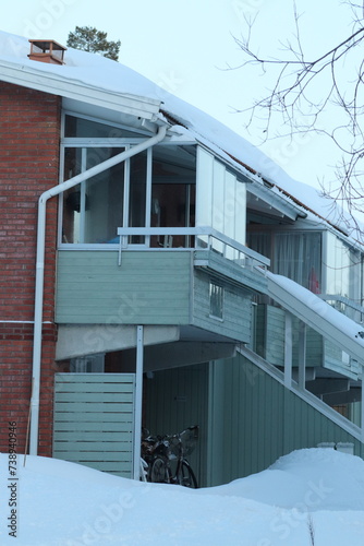 Brick house in a residential area in Östersund. Winter with a lot of snow after snowfall on footpaths and in the parking lot. Pine trees near houses with snow on the twigs. Winter in Östersund.

 photo