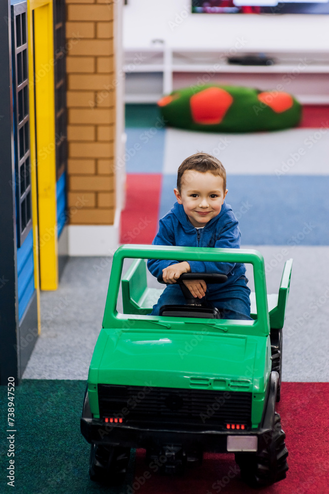 Little boy, happy smiling child rides a children's plastic electric car in the playroom. Photography, portrait, childhood concept, lifestyle. Little boy, happy smiling child rides a children's plastic electric car in the playroom. Photography, portrait, childhood concept, lifestyle.