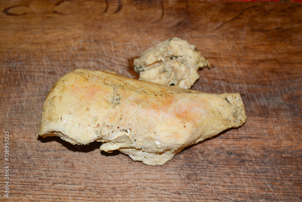 Fototapeta premium A piece of chicken fillet boiled in spices on a wooden board. Cooking stage: boiled chicken fillet