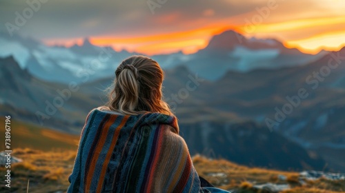 woman with a coat on a mountain top at sunset with the sun in the background in high resolution and quality