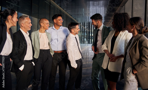 Presentation meeting of male team leaders smiling introducing themselves standing in hallway of the business center. Group of multiracial office workers in suits happy looking cheerful at their CEO