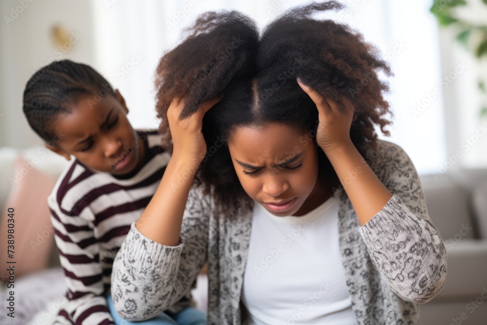Obraz premium Concerned Child with Stressed Mother. Young African American girl comforting her stressed mother at home, depicting family support and maternal stress.