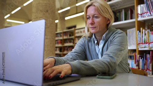 Female adult student learning new educationalvsubject in library Middle aged woman using laptop in studying and research for Scientific materials online in Internet. Upgrade professional qualification photo