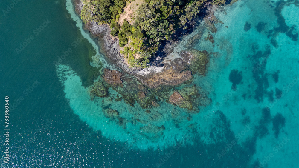 Obraz premium Aerial view of an island surrounded by crystal blue water and rocks