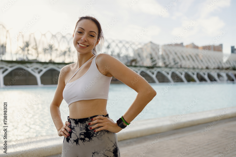 Fototapeta premium Pretty woman in sportswear have a rest after workout outside standing on building background