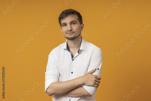 a man in a white t-shirt smiles at the camera. yellow background.