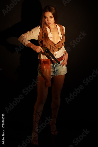 Beautiful young woman with old wild west revolver low key portrait