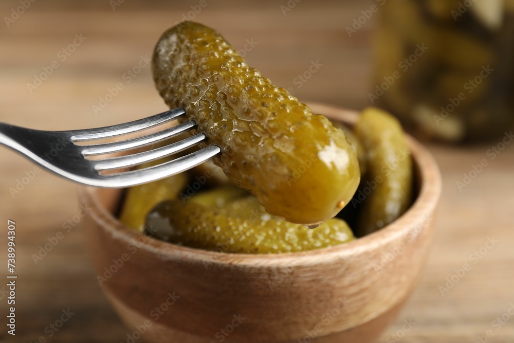 Eating tasty pickled cucumber at table, closeup Eating tasty pickled cucumber at table, closeup