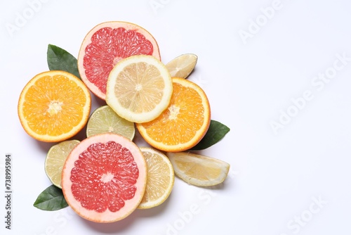 Different cut citrus fruits and leaves on white table  flat lay. Space for text