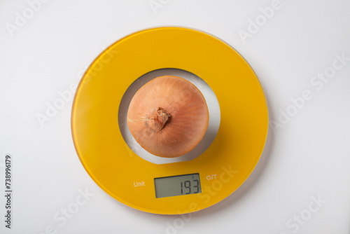 A Spanish yellow raw onion head on rounded yellow kitchen electronic scale