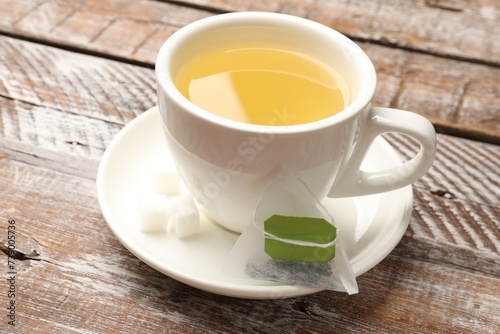 Tea bag and cup of aromatic drink on wooden rustic table, closeup