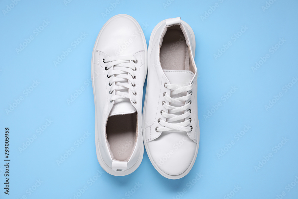 Pair of stylish white sneakers on light blue background, top view Pair of stylish white sneakers on light blue background, top view