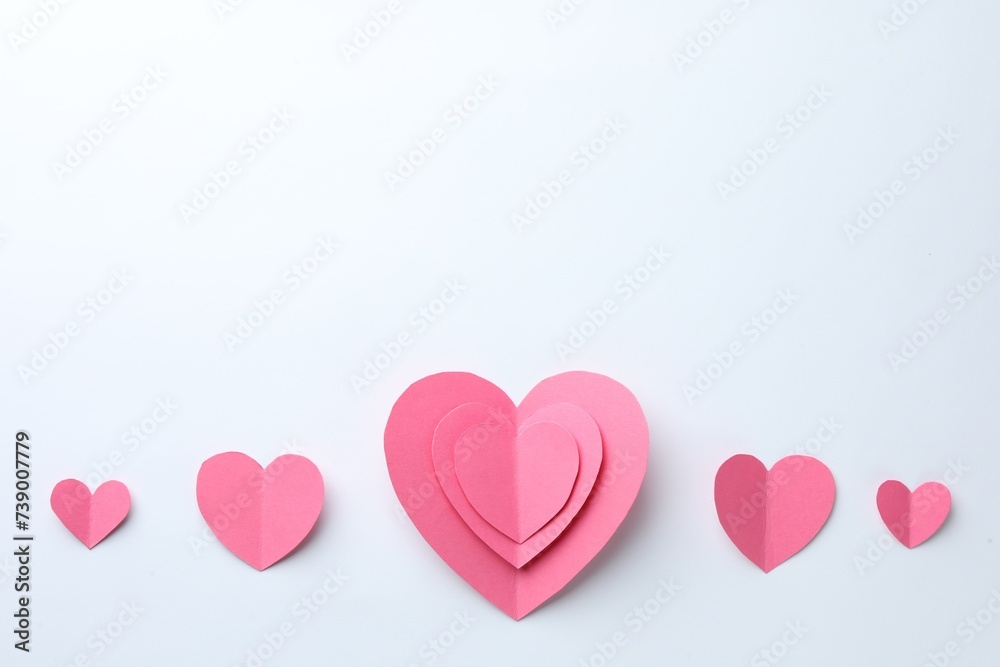Pink paper hearts on white background, flat lay. Space for text