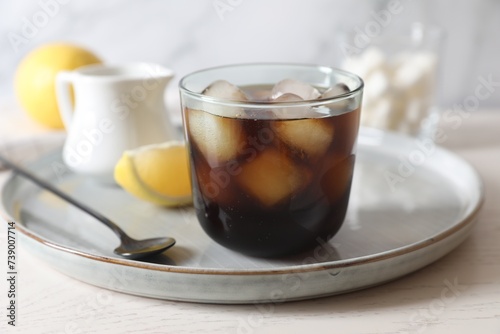 Refreshing iced coffee in glass and spoon on white wooden table, closeup