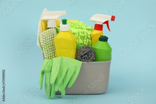 Different cleaning products in basket on light blue background