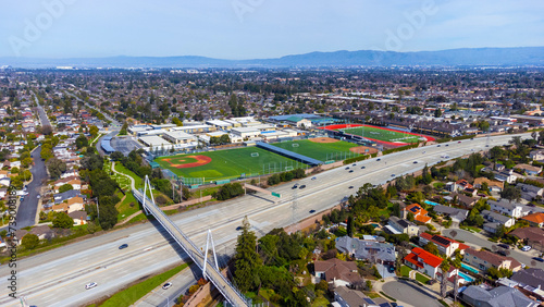 Aerial view of a high school grounds in residential neighborhood near Don Burnett bicycle pedestrian a cable-stayed bridge over Interstate 280, spanning Cupertino and Sunnyvale, California