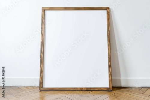 photo of a large blank frame leaning against a white wall. Frame is wood. resting on wooden parquet, close up, photo taken straight ahead