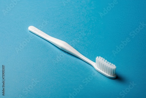 A white toothbrush rests delicately on a vibrant blue background. Soft bristle brush denotes care and hygiene while blue reflects tranquility and freshness.