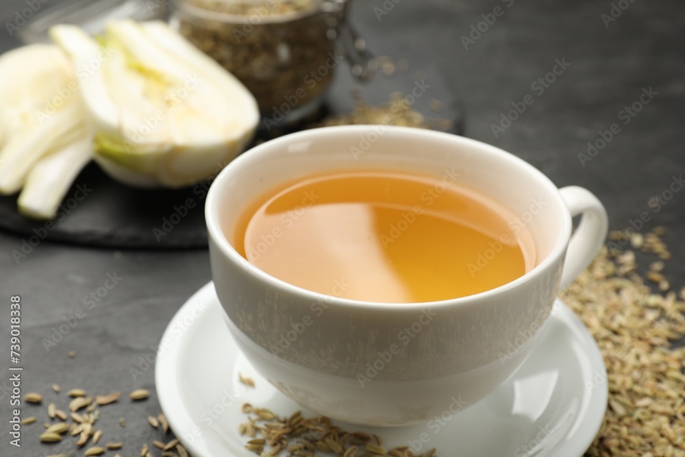 Aromatic fennel tea in cup and seeds on black table, closeup Aromatic fennel tea in cup and seeds on black table, closeup
