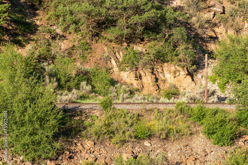 In a summer morning, the railroad track on the edge of the Colorado river in the Glenwood Canyon, White River National Forest (Glenwood Springs, Colorado, United-States) photo