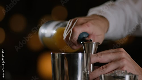 Bartender measures liquor in a jigger for a cocktail