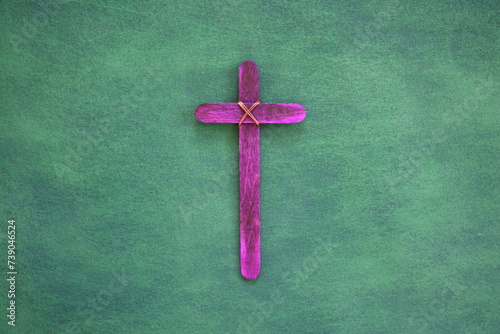 Purple wooden cross flat lay in green background. Holy week and lent season celebration concept. photo