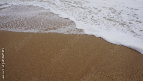 Background image pattern of sea shore with sea waves on sand photo