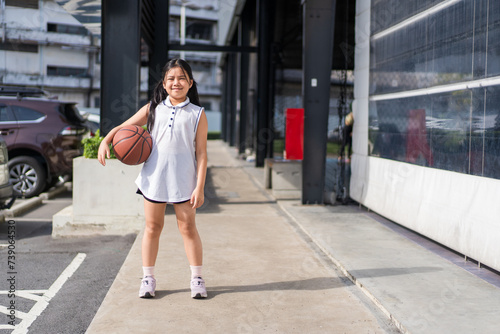 basketball and asian child or kid girl standing holding to playing and smile training to learning ball at sports stadium school or basketball court for exercise on sport day and holiday with copyspace photo