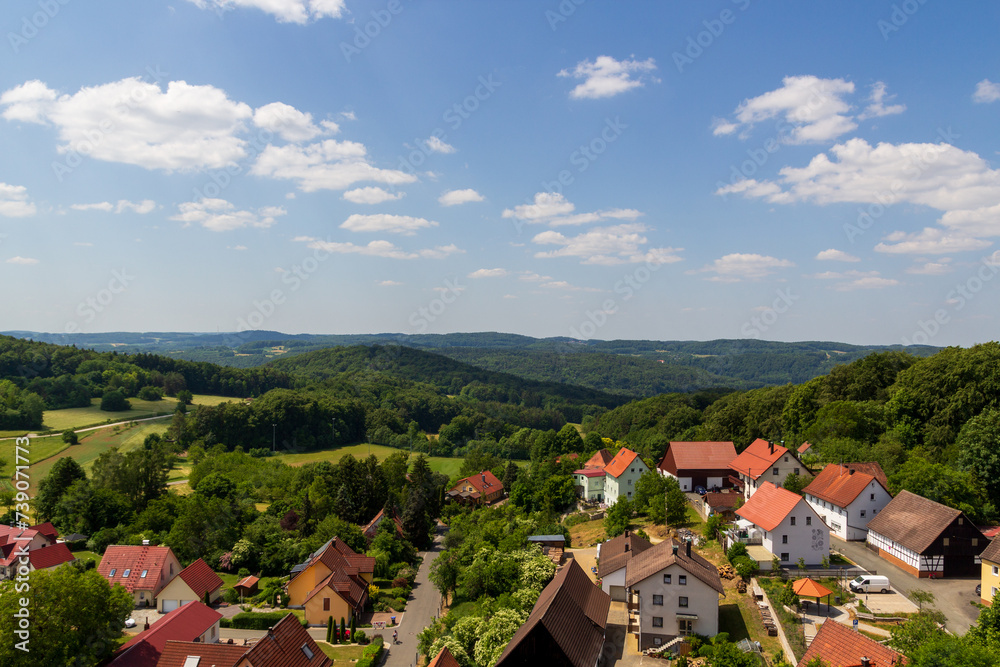 Rural scene with hill panorama, meadows and houses of village Wichsenstein in Franconian Switzerland, Germany