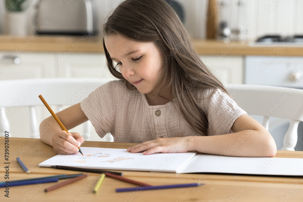 Little girl painting pictures in paper sketchbook with pencils. Cute kid sit at table in cozy domestic kitchen drawing in album, looking focused, enjoy creative activity, favourite hobby alone at home Little girl painting pictures in paper sketchbook with pencils. Cute kid sit at table in cozy domestic kitchen drawing in album, looking focused, enjoy creative activity, favourite hobby alone at home