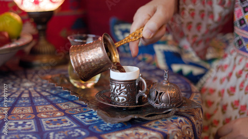 Pouring turkish coffee from cezve into cup. photo