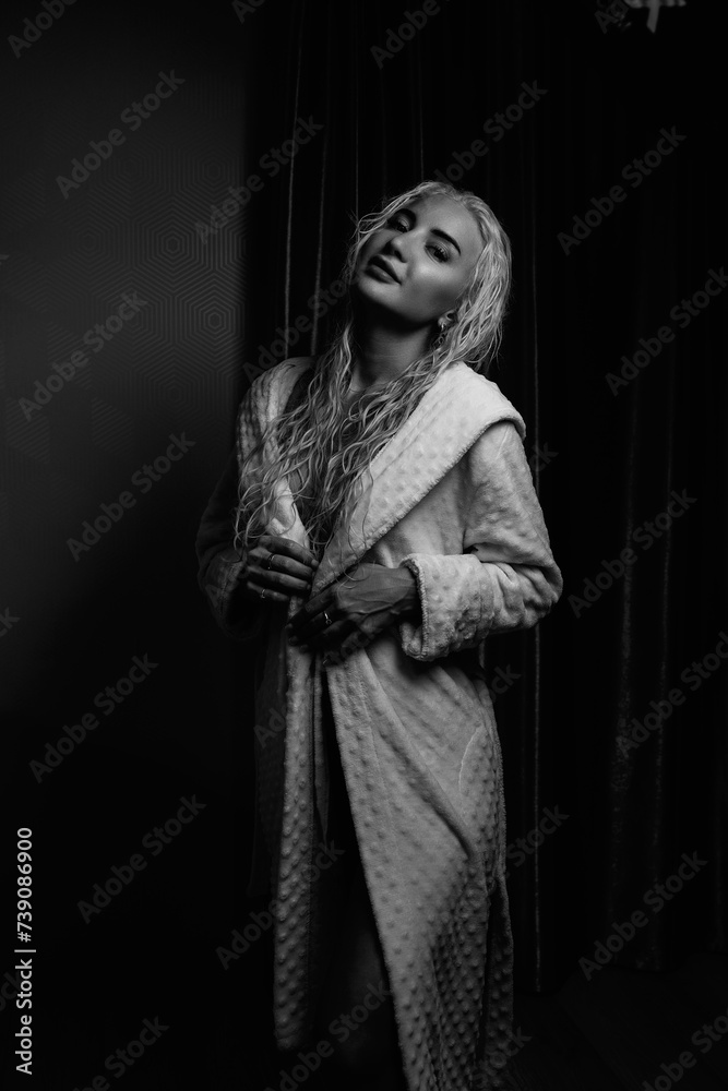 Portrait of a young girl with blond hair in a dressing gown in a low key.