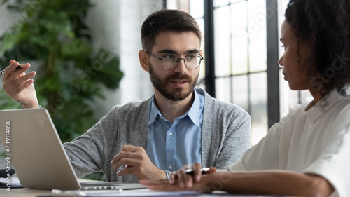 Male financial adviser giving consultation to female client concerning business issues. Young manager promoting bank products and investment options to customer. Coworkers discussing work project