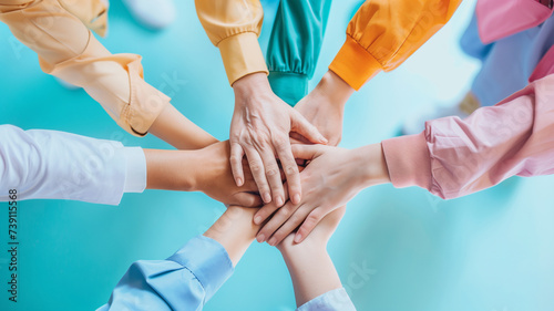 A top view of diverse hands coming together in a symbolic gesture of teamwork and solidarity, with a vibrant blue background enhancing the sense of unity