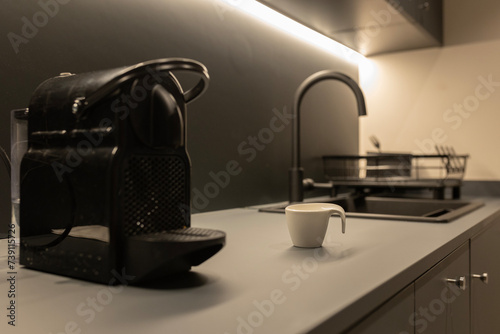 Kitchen where a black coffee maker is observed in the foreground out of focus
