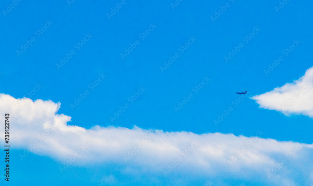 Passenger airplane flies in blue sky with clouds in Mexico.