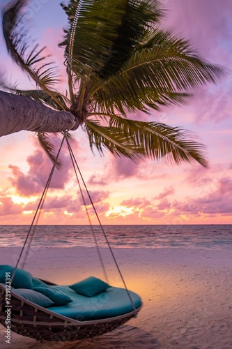 Tropical sunset beach background. Summer island landscape beach swing hammock hanging on palm tree, romantic sea sand sky beach. Beautiful couple beach scene vacation tourism holiday. Honeymoon resort