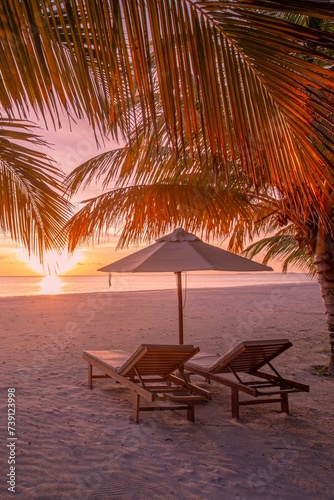 Beautiful tropical sunset coast  two sun beds chairs umbrella under palm trees. Closeup white sand  sea view horizon colorful twilight sky calm and relaxation. Inspire beach resort tourism landscape