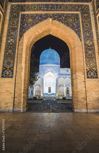 Facade of the Gur Emir mausoleum with mosaics and brick walls at night with illumination in the ancient city of Samarkand in Uzbekistan, oriental architecture in the evening