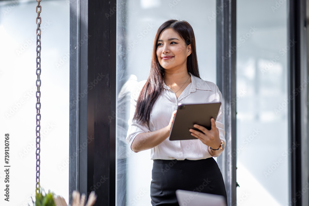 Young asian busy professional business woman executive, female company worker or manager holding digital tablet technology device working standing in modern corporate office. Young asian busy professional business woman executive, female company worker or manager holding digital tablet technology device working standing in modern corporate office.
