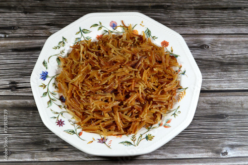 A plate of of browned in Butter sweet Egyptian vermicelli cooked with water and sugar in a cooking pot,. traditional Egyptian dessert in late lunch and early dinner, an Egyptian popular recipe photo