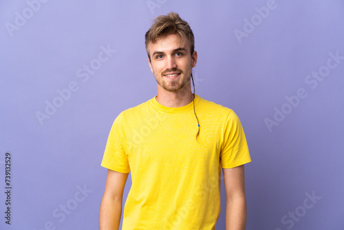 Young handsome blonde man isolated on purple background laughing