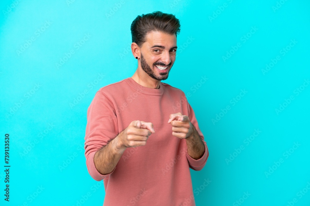Young caucasian man isolated on blue background surprised and pointing front Young caucasian man isolated on blue background surprised and pointing front