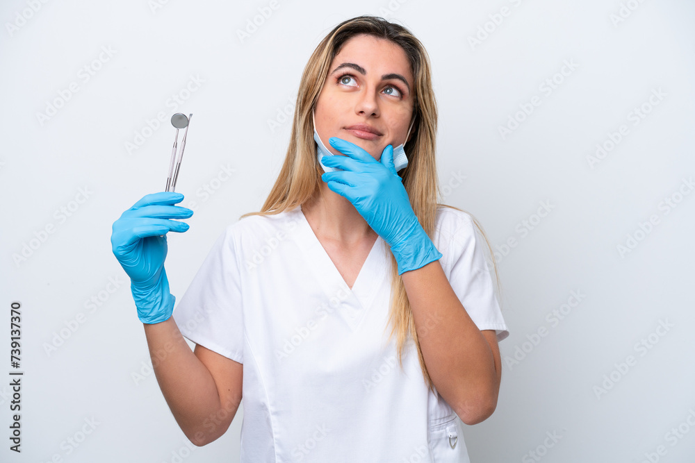 Dentist woman holding tools isolated on white background having doubts Dentist woman holding tools isolated on white background having doubts