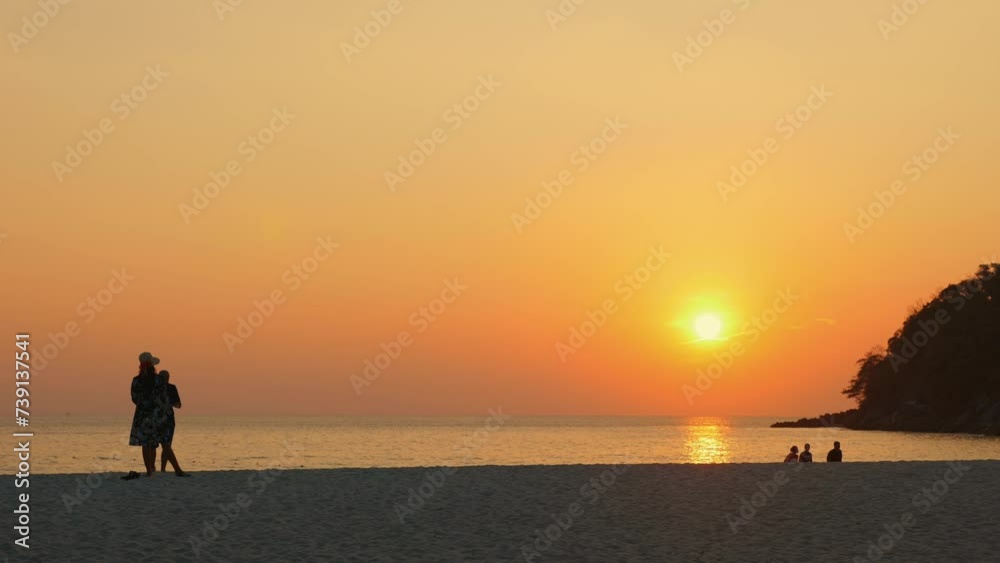 Couple enjoying peaceful walk on beach at sunset, with silhouettes against orange sky. Tranquility and connection with nature. Couple enjoying peaceful walk on beach at sunset, with silhouettes against orange sky. Tranquility and connection with nature.
